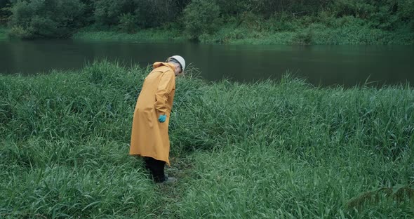 Environmentalist in Raincoat Takes Sample of Water From Reservoir Into Test Tube