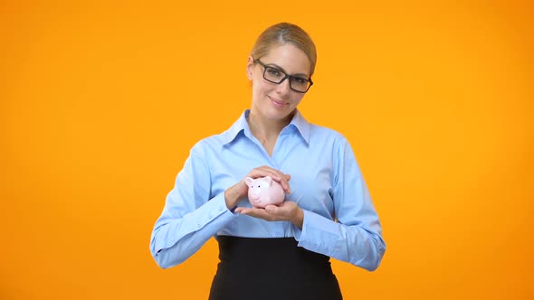 Female Bank Manager Holding Piggybank in Hand, Pension Fund, Deposit Insurance alt