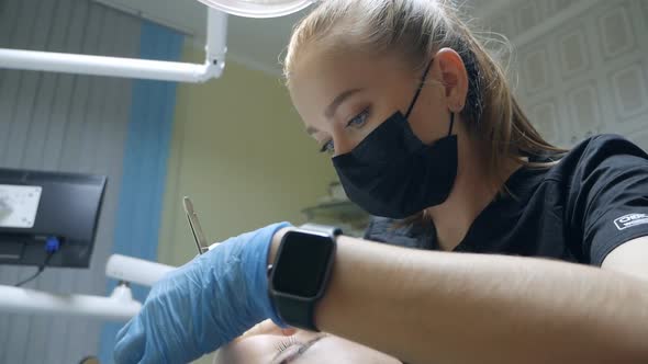 Young Female Dentist Curing Tooth Cavity