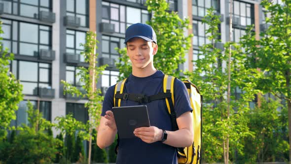 Portrait Smiling Man Courier Food Delivery with Thermal Backpack Uses Tablet alt