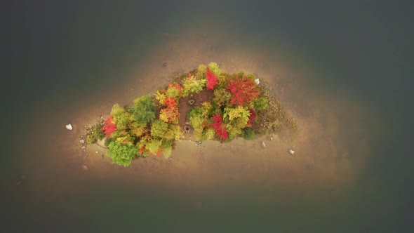 Top Down Aerial View Above Scenic Small Island with Fall Trees in Cinematic Lake alt