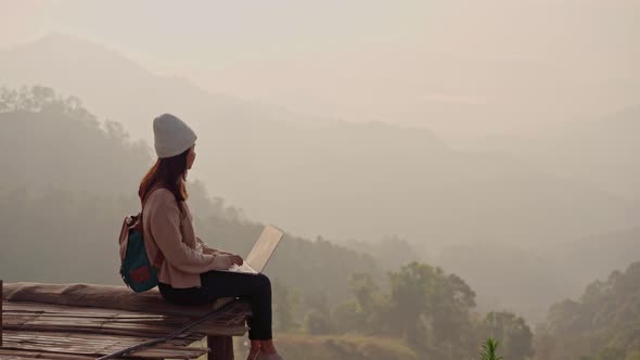 Young woman freelancer traveler working online using laptop and enjoying the beautiful nature