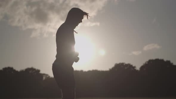 Man In Park Skipping Rope To Keep Fit With The Dying Sun Behind Him In Slow Motion - Ungraded alt