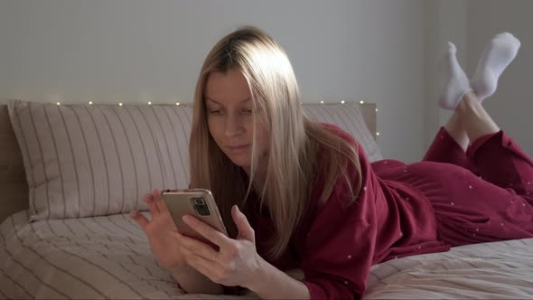 Woman Lying in Bed with Phone alt