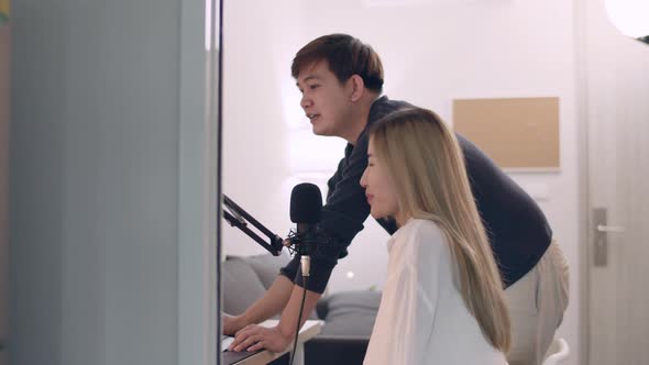 Young Asian male teaching his woman friends music artist recording voice singsong.