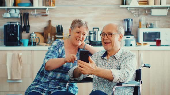 Smiling Disabled Man and His Wife Using Smartphone alt