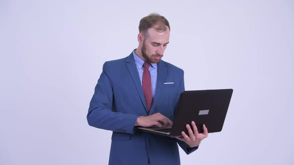 Happy Bearded Businessman Thinking While Using Laptop