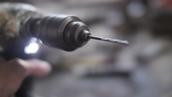 Spinning drill bit in males hand close up alt