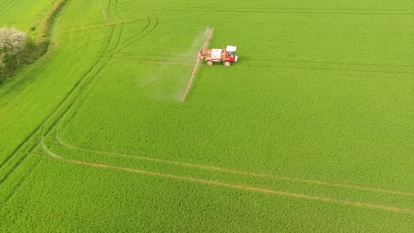 Side view of crop sprayer working in field spraying crops with herbicides or pesticides alt