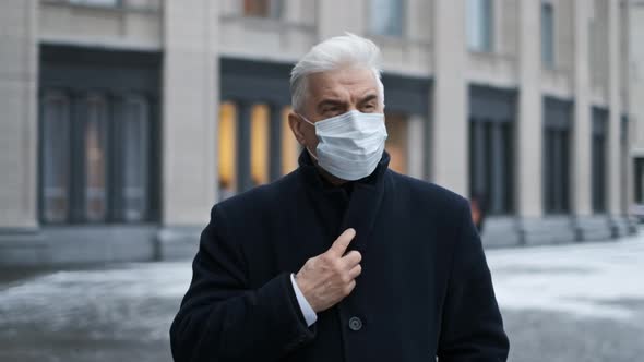Retired Sick Man in Black Coat Mask Walks on Street During Coronavirus Pandemic alt