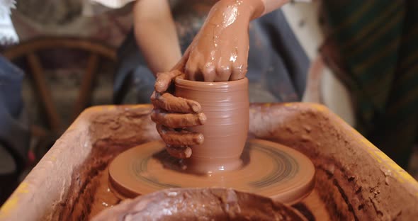 Pottery. Hands Form A Jug Of Clay On A Potter's Wheel