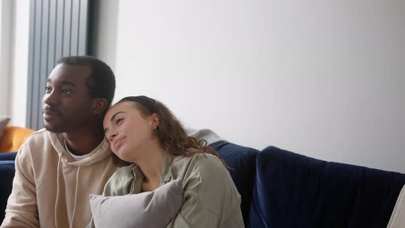 Loving Young Couple Relaxing At Home Sitting On Sofa Whilst Watching Romantic Film On TV Together alt