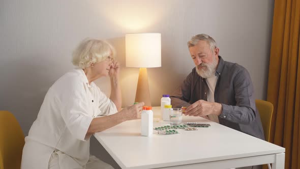 Elderly Couple Understands a Variety of Medicines Sitting in the Kitchen