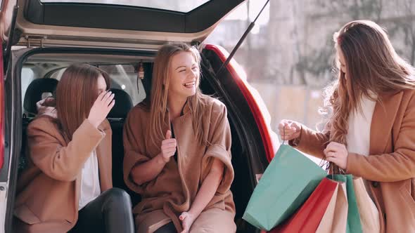 Attractive Girls Have Shopped and Checking Purchases at the Car Back alt