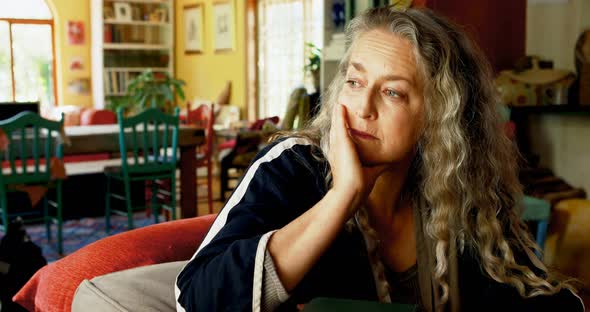 Mature woman relaxing on sofa in living room at home 4k alt