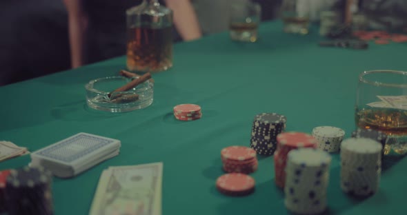 Chips Cards Money and Cigars are on the Green Gaming Table alt