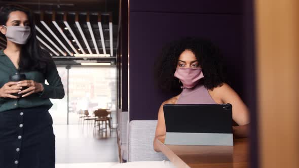 Two Businesswomen In Masks Have Socially Distanced Meeting In Office Touching Elbows During Pandemic alt