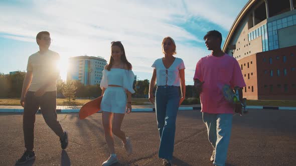 Four Difethnic Young Students Walking on Sunny Street Communicating Sharing Stories Laughing alt