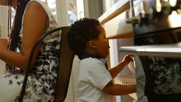 Side view of cute little black son looking in colander in kitchen of comfortable home 4k alt