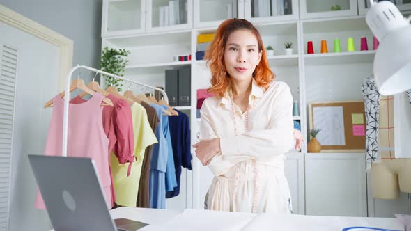 Portrait of Asian tailor woman look at camera after success in make new clothes in tailoring atelier alt