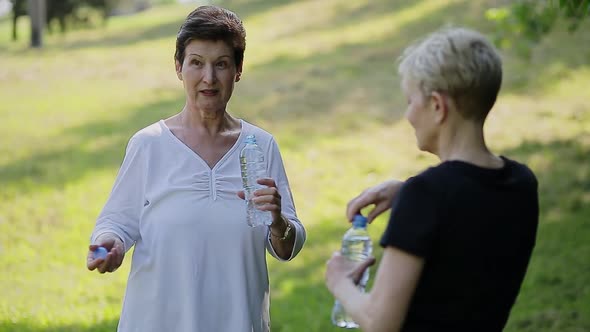 Cheerful Senior Women Talking and Holding a Bottle of Water