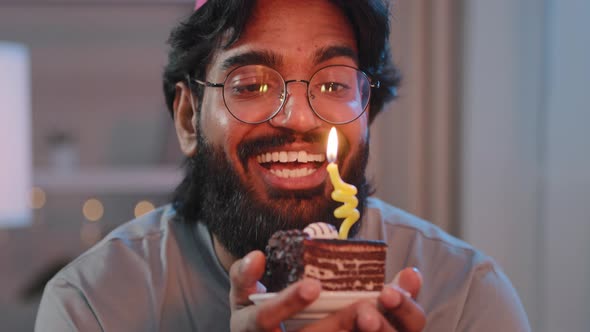 Portrait of Multiracial Man with Thick Black Beard in Glasses and Festive Hat with Cake in Light in alt