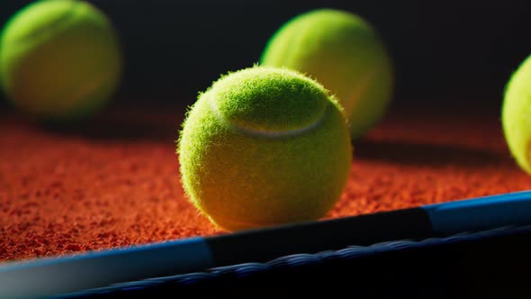 Camera rotating around a tennis ball lying next to racket on the court at night alt