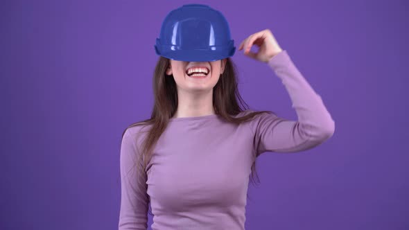 The Optimistic Girl Wears Her Engineer's Blue Helmet Smiles Broadly Raises It Looks Playful on Her alt