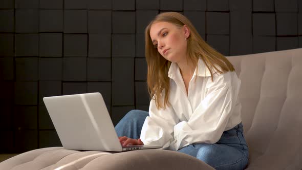 Young Woman Using Laptop While Sitting on a Chair