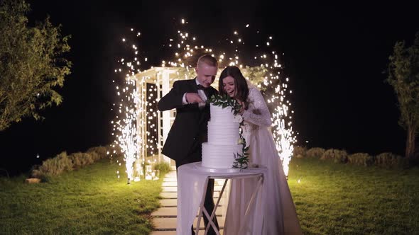 Newlyweds Cut the Wedding Cake Lovely Bride and Groom Couple Cutting Dessert with a Knife Outdoors alt