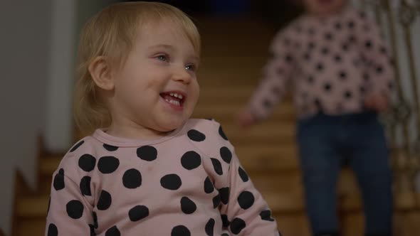 Joyful Cute Baby Girl Dancing in Slow Motion with Blurred Unrecognizable Twin Sister at Background alt