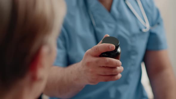 Close Up of Nurse Hand Holding Bottle of Pills and Capsules alt