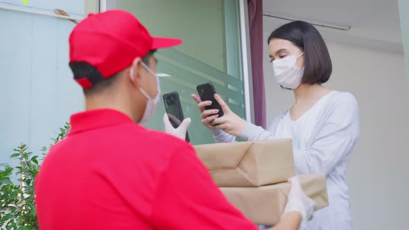 Asian young cute girl wear mask, receive boxes from postman delivering package of goods at the door. alt