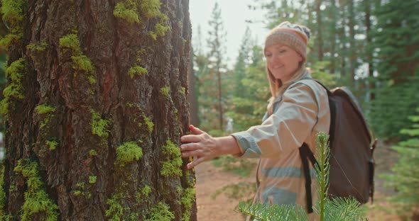 Woman Supporting Environment Palm Tree Trunk with Bark Covered By Green Moss  alt