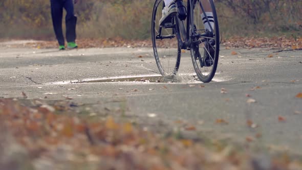 Cyclist Riding On Road Bike. Bike Wheels Rides Through Puddle. Cycling On Puddle And Splashing Water alt