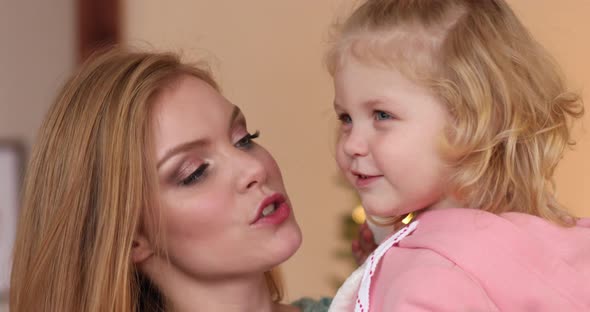 Young Beautiful Mother Kisses Her Daughter in the Cheek