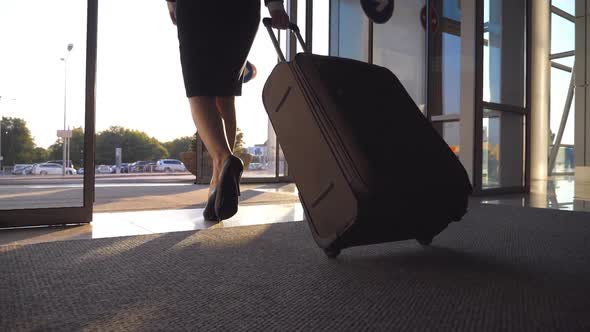 Business Lady Leaving Airport Through Automatic Glass Door with Her Luggage. Young Woman in Heels alt