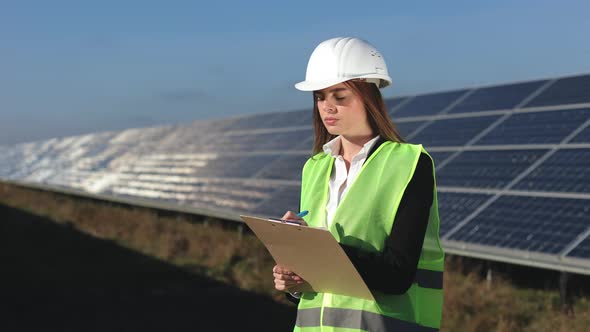 A Female Engineer is Conducting an Inspection of Solar Panels alt