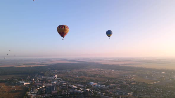 Colorful Hot Air Balloons Flying Over Green Park in Small European City at Summer Sunrise, Aerial alt