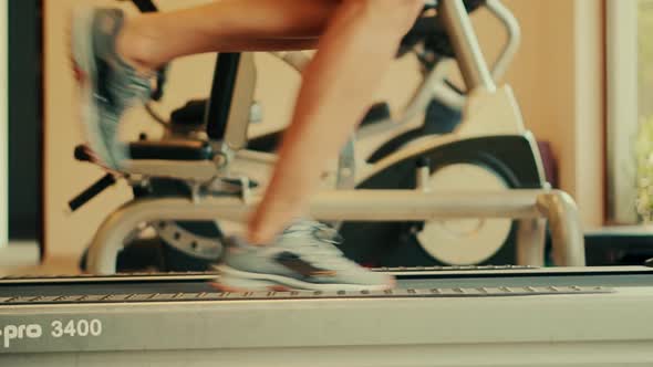 Fit Sportsman Running Indoors. Foot Sneakers Fitness Jogging Treadmill.Muscular Legs Exercise In Gym alt