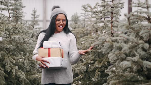 Beautiful African Woman with Pile of Christmas Presents at Spruce Tree Market alt