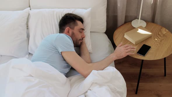 Man Sleeping in Bed Checking Time on Smartphone