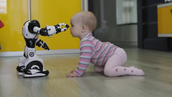 The Little Girl Carefully Looks at the Toy Robot and Dances with Him. Modern Robotic Technologies