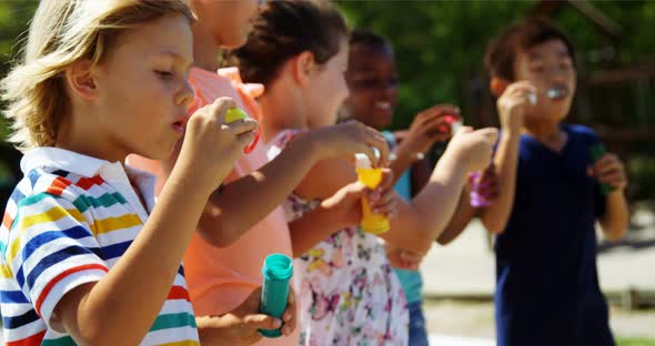 Schoolkids playing with bubble wand in playground alt