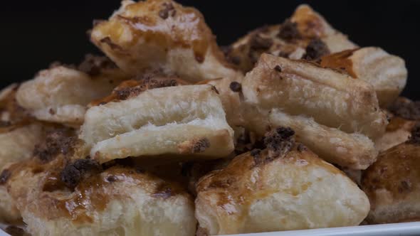 Baked puff pastry with toppings. Puffs with cheese on white plate rotating in front of camera alt
