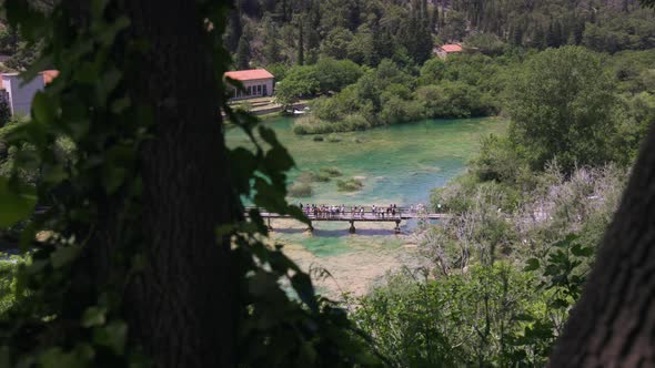 A crowd of tourist gather on a bridge admiring the beautiful waterfalls and turquoise river in Krka alt