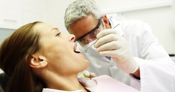Dentist examining a female patient with tools alt