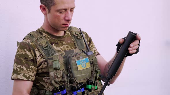 Ukrainian Military Man in Combat Camouflage and Body Armor Attaches a Silencer to His Assault Rifle alt