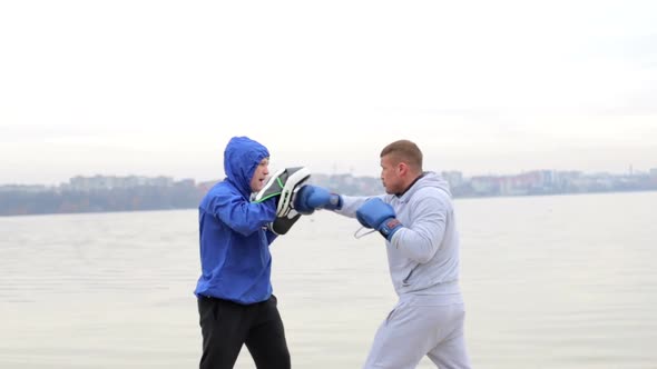 A young fighter in a gray suit runs with dumbbells in his hands and waving his arms alt