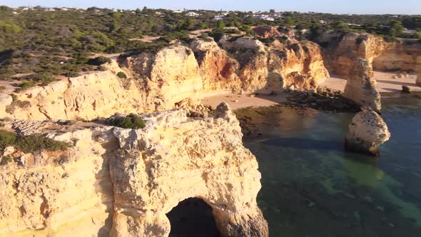 Aerial view of man standing on cliff above arch in Marinha Bay alt